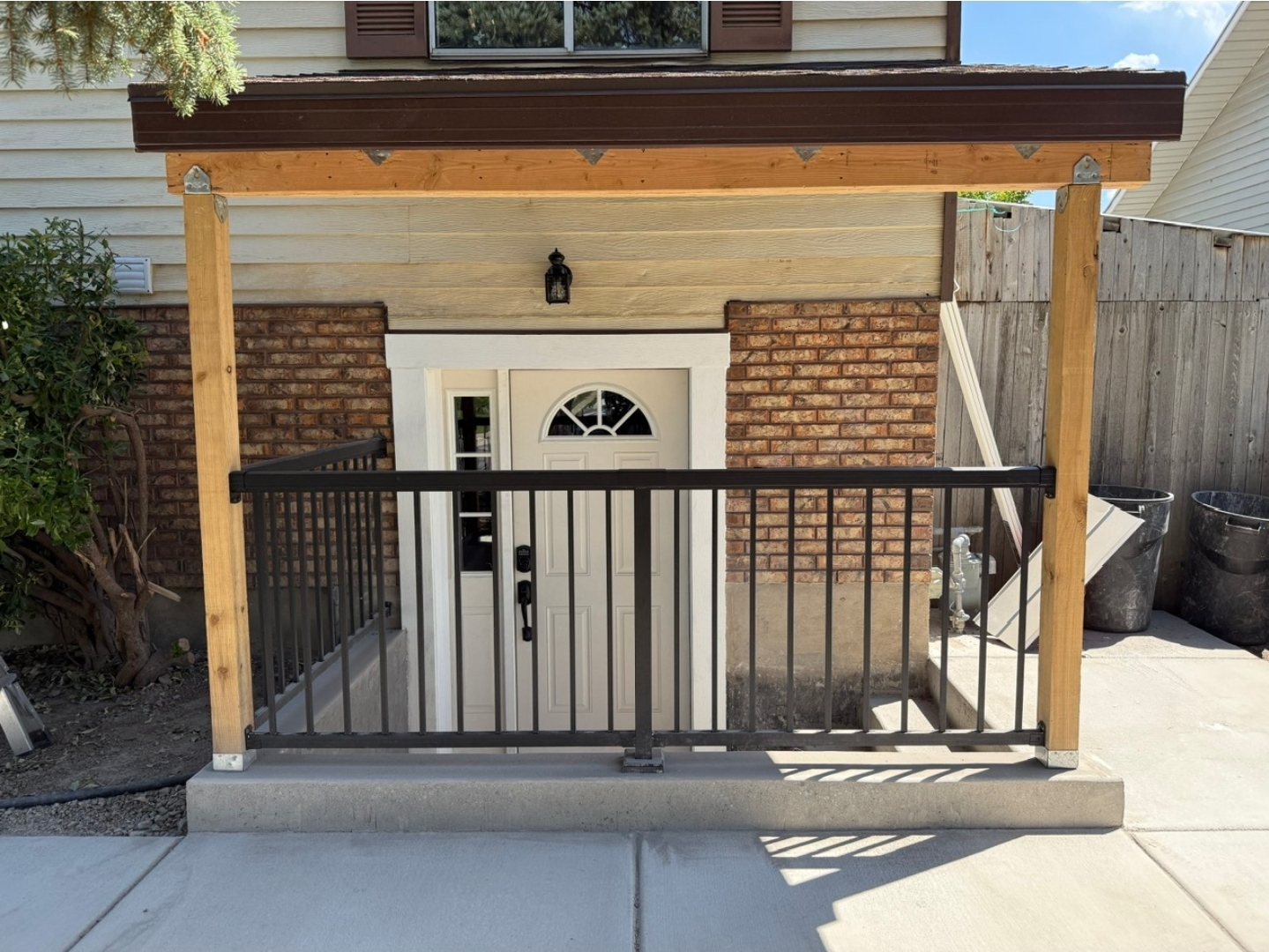 New covered front entry with cedar posts, brick accents, and metal railing